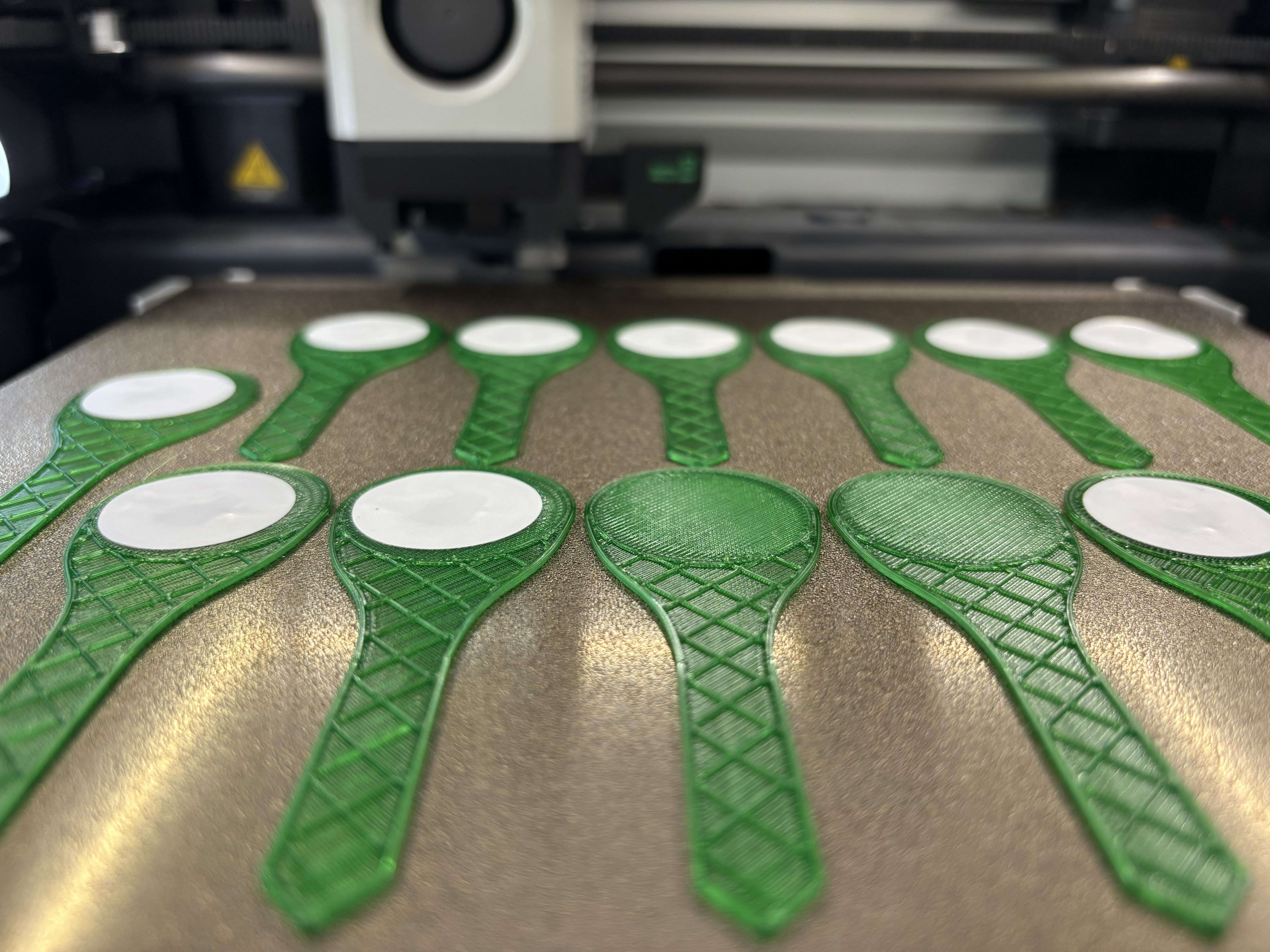 3D printer bed with several tags half way through printing, some have NFC stickers applied